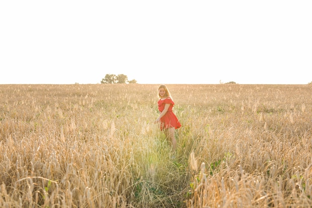 Chica de vestido rojo en el campo. Vista trasera