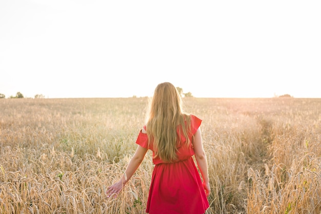 Chica de vestido rojo en el campo. Vista trasera