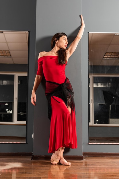 Chica en vestido rojo está entrenando en estudio de baile