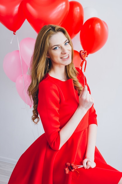 Chica en vestido rojo con globos en forma de corazón