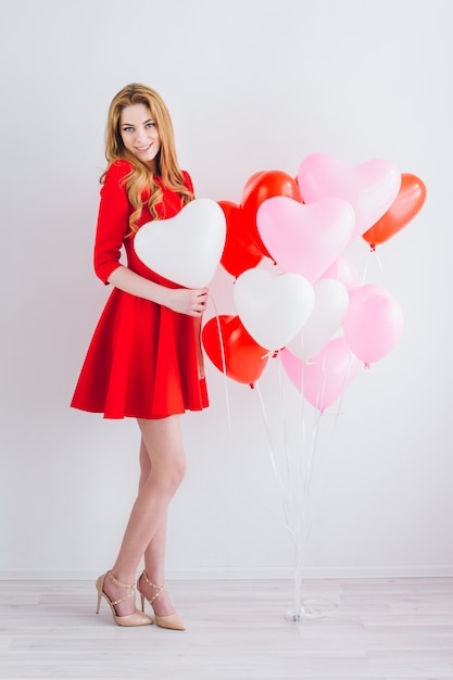 Chica en vestido rojo con globos en forma de corazón