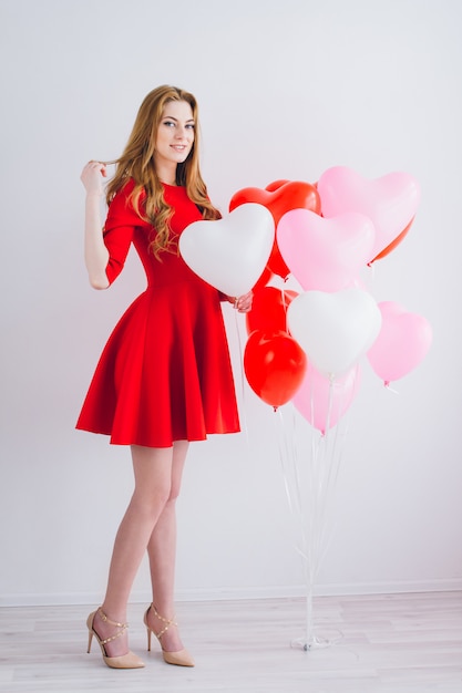 Chica en vestido rojo con globos en forma de corazón