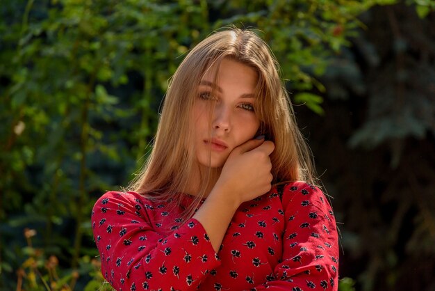 Una chica con un vestido rojo con el pelo largo sobre un fondo de vegetación en verano. hermosa chica en la naturaleza