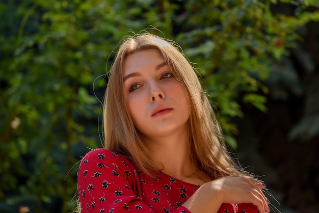 Una chica con un vestido rojo con el pelo largo sobre un fondo de vegetación en verano. hermosa chica en la naturaleza