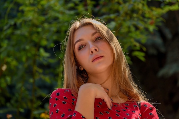 Una chica con un vestido rojo con el pelo largo sobre un fondo de vegetación en verano. hermosa chica en la naturaleza