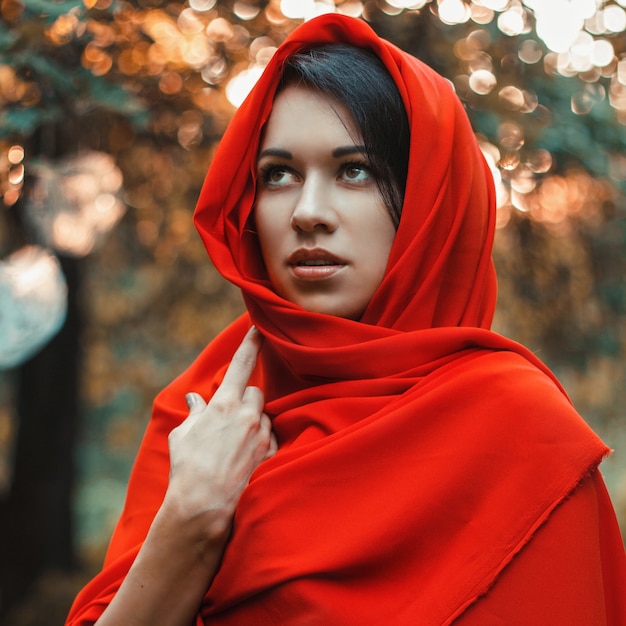 Chica en un vestido rojo de pie en el jardín con corazones