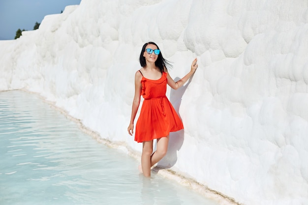 Chica en vestido rojo sobre travertinos blancos