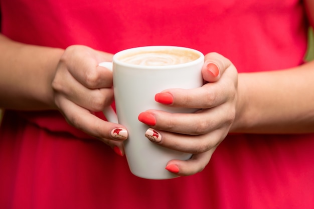 Chica con un vestido rojo sosteniendo una taza de café