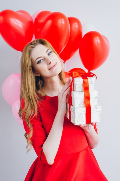 Chica en vestido rojo tiene cajas con regalos