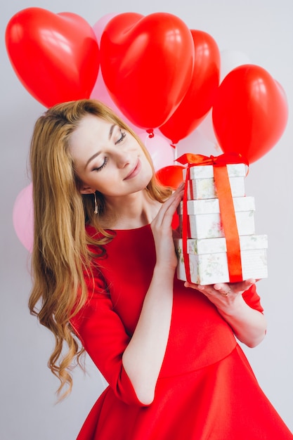 Chica en vestido rojo tiene cajas con regalos