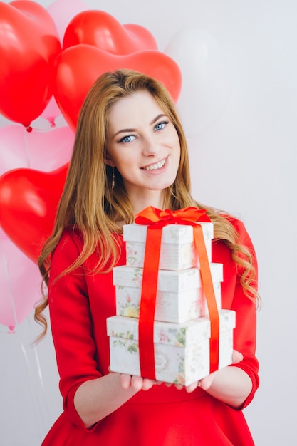 Chica en vestido rojo tiene cajas con regalos