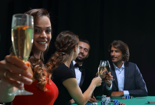 Chica en vestido rojo con vaso en mano jugando a la ruleta