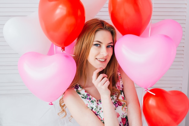 Chica en vestido romántico con globos en forma de corazón