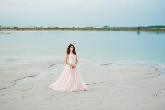 Chica con un vestido rosa está caminando por la arena blanca del desierto