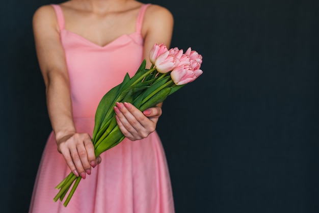 Chica en un vestido rosa con un ramo de tulipanes