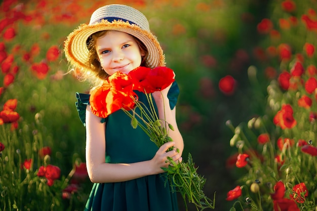 Chica en vestido y sombrero de paja al aire libre en el campo de amapolas