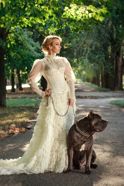 Chica con un vestido viejo con volantes y un gran perro oscuro