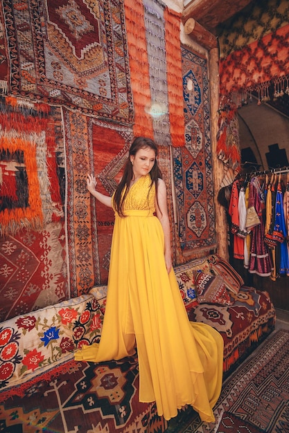 Chica con un vestido volador amarillo en el suelo contra el fondo de las alfombras