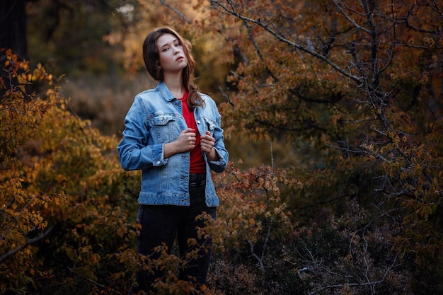 Chica viaja en el bosque de las montañas Una chica con una chaqueta de mezclilla y una camiseta roja Montañas en otoño Viajes Estilo de vida y concepto de supervivencia