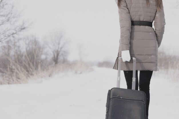 Chica viaja con una maleta. Camino de invierno y una niña.