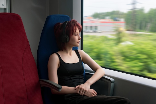 Chica viaja en un tren de cercanías y mira por la ventana a un paisaje exterior borroso en movimiento