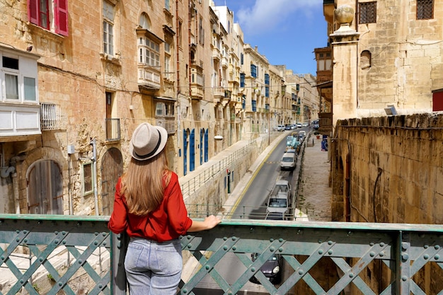 Chica viajera en el puente de hierro mirando edificios históricos en el centro de la ciudad de Valletta Malta