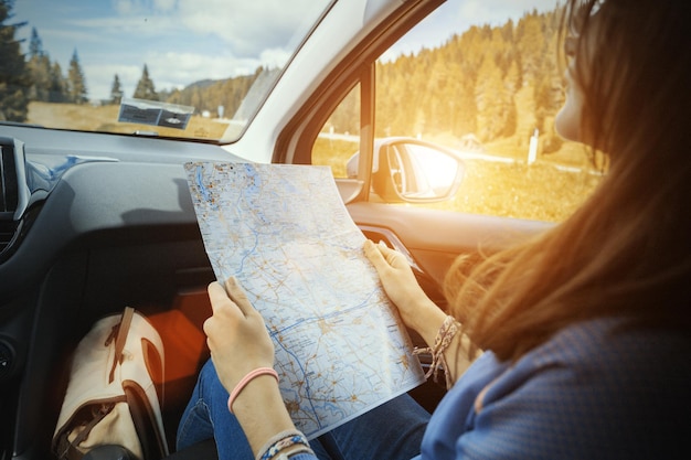 Chica viajero mira el mapa sentado en el coche, Italia