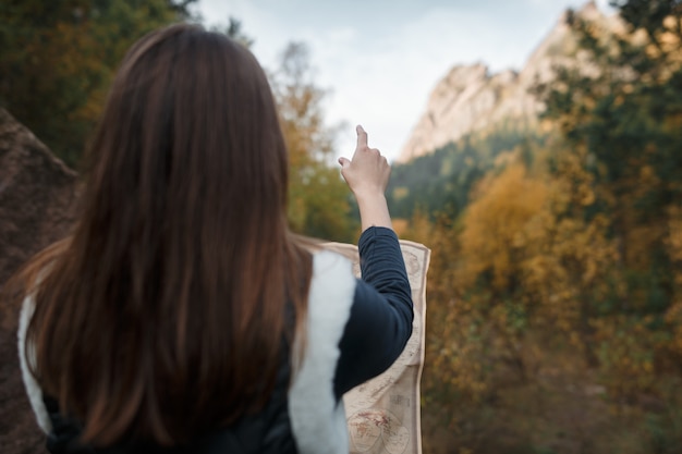 Chica con un viejo mapa en las montañas de otoño