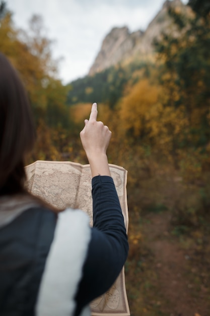 Chica con un viejo mapa en las montañas de otoño