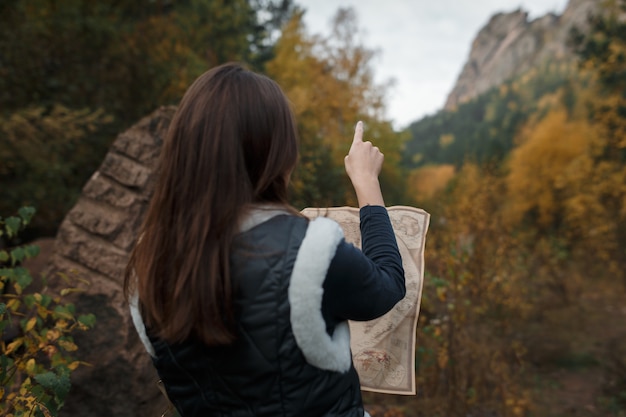 Chica con un viejo mapa en las montañas de otoño