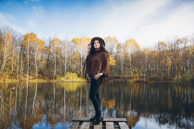 Chica en un viejo puente de madera sobre un lago