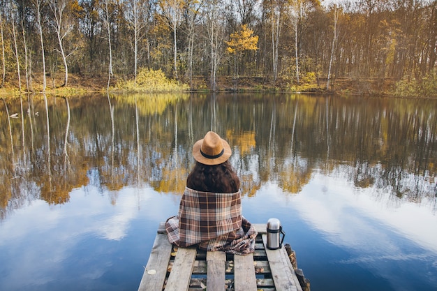 Chica en un viejo puente de madera sobre un lago