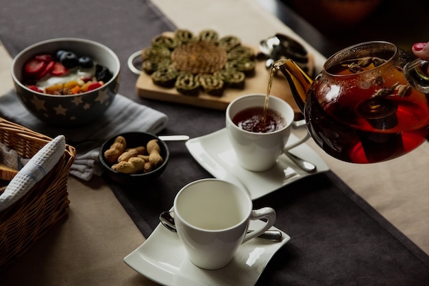 Chica vierte té negro en una taza para el desayuno