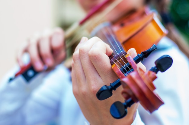 Chica con un violín en un borroso brillante del bokeh