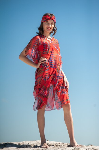 Chica vistiendo ropa de playa y posando en la playa de arena