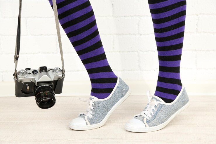 Foto chica en zapatillas de deporte con cámara de fotos retro en la habitación