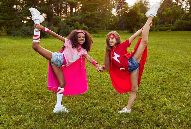 Chicas alegres en trajes de superhéroe de pie en el parque