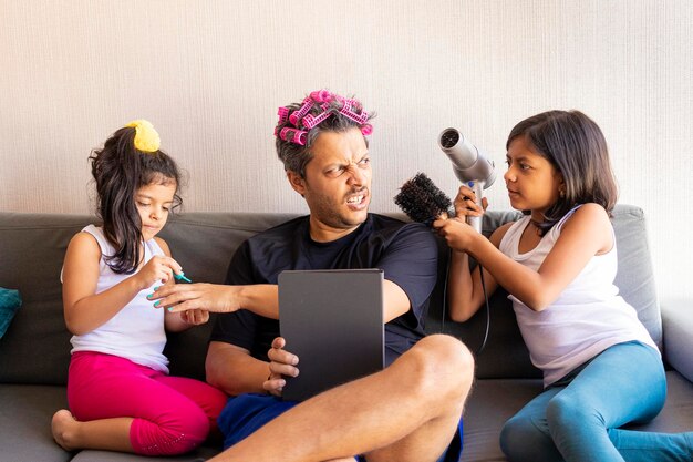 Foto las chicas se arreglan con el padre mientras están sentadas en el sofá.