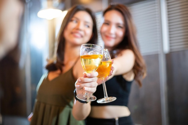 Chicas asiáticas brindando con una copa de vino a la cámara por celebrar en la fiesta