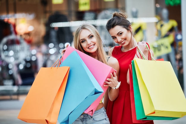 Chicas atractivas en centro comercial con bolsas