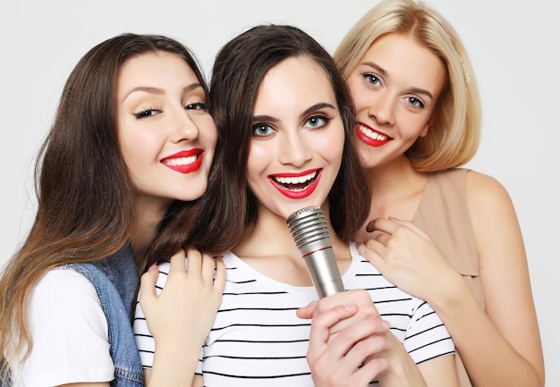 Chicas de belleza con un micrófono cantando y divirtiéndose juntas