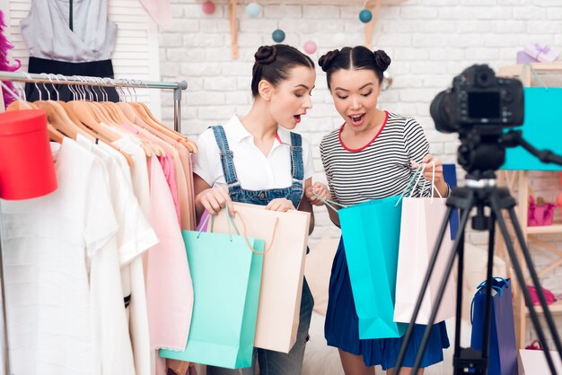 Las chicas bloggers presentan muchos bolsos coloridos a la cámara.