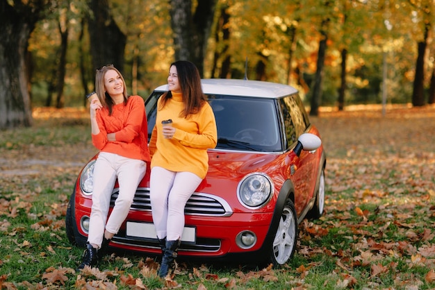 Chicas caminando en el parque de otoño en coche rojo concepto de estado de ánimo de otoño