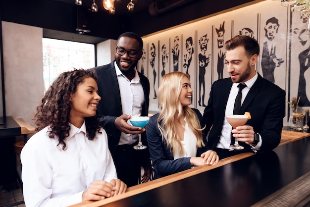 Chicas y chicos se comunican entre sí en un bar.