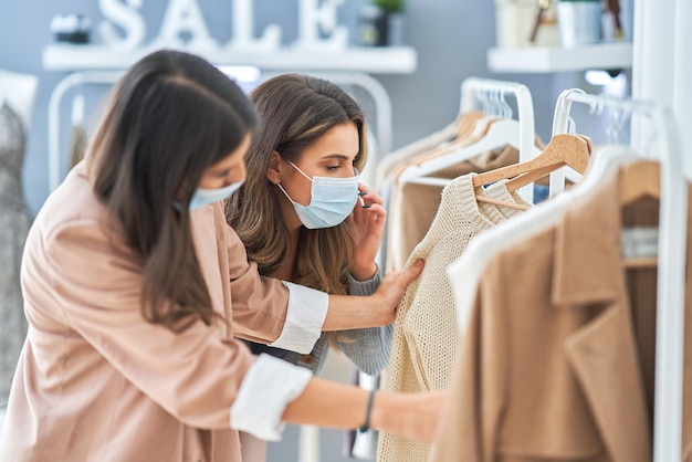 Chicas de compras en la tienda con ropa con máscaras. Foto de alta calidad