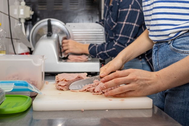 Chicas cortando jamón en un restaurante local de pizza y giroscopios.