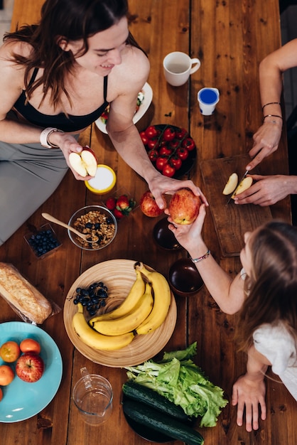 Foto chicas deportivas en la cocina comiendo manzanas y frutas.