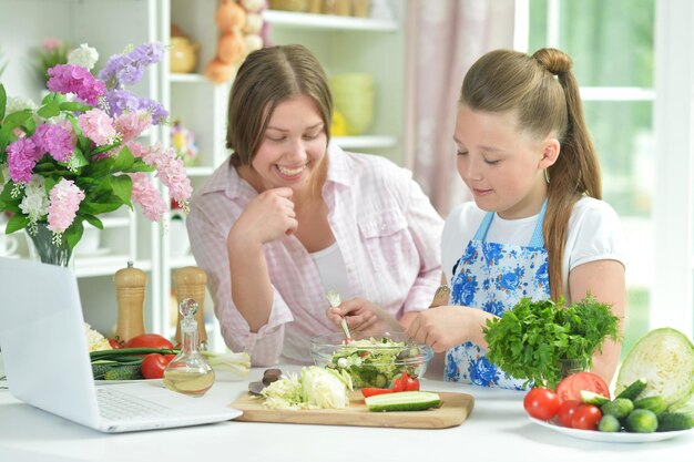Chicas divertidas preparando ensalada fresca