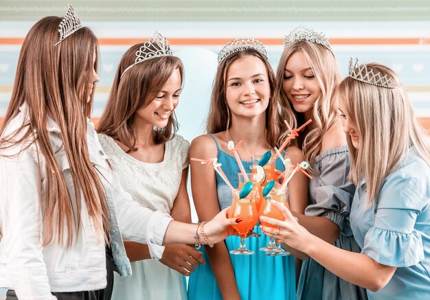 Chicas felices en diademas con cócteles en la fiesta de celebración