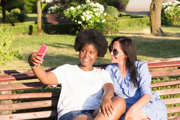 Chicas felices de diferentes nacionalidades se toman selfies en el verano.